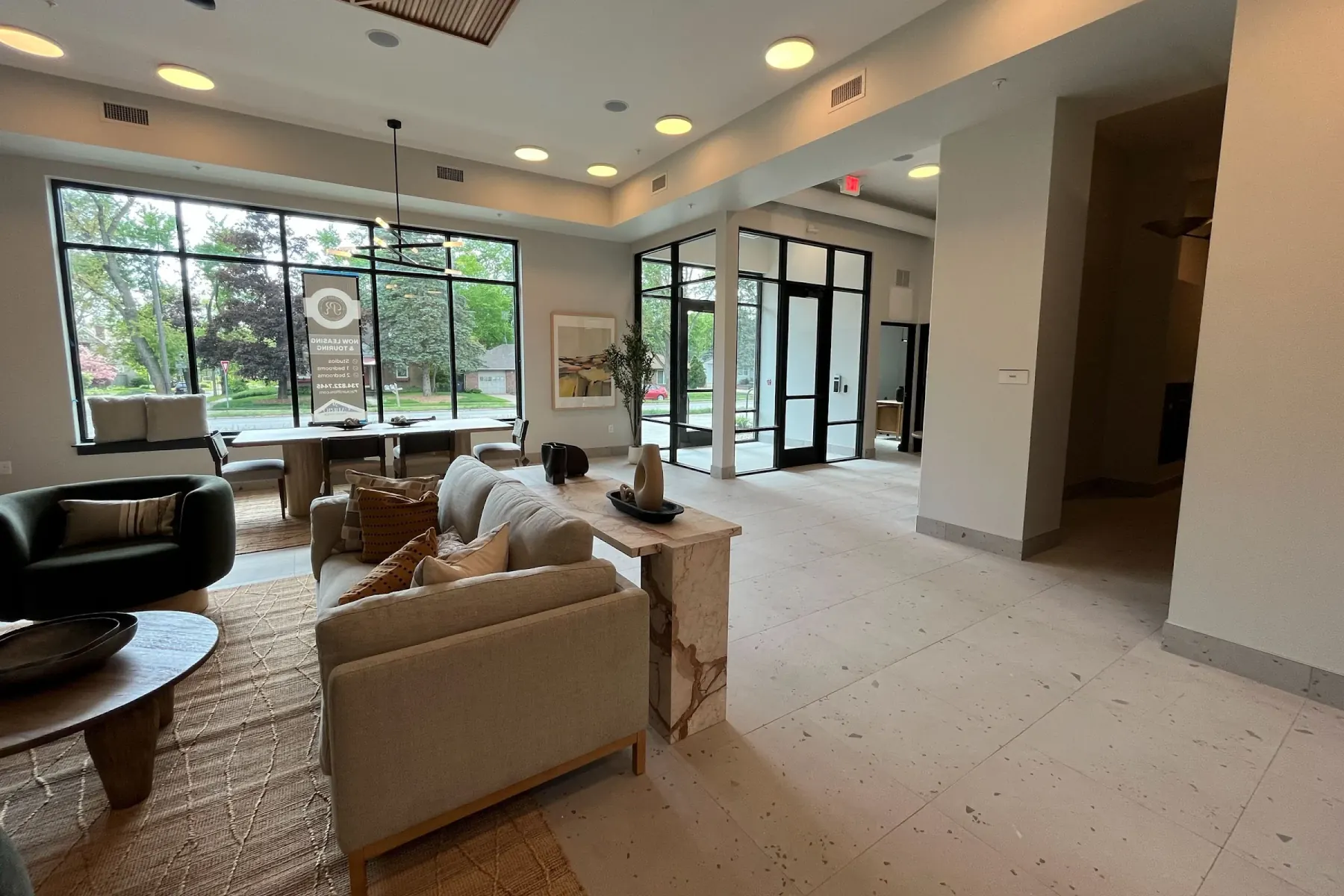 Open clubhouse seating area at Packard Row with linen sofas, accent chairs, and a marble communal table beside oversized windows