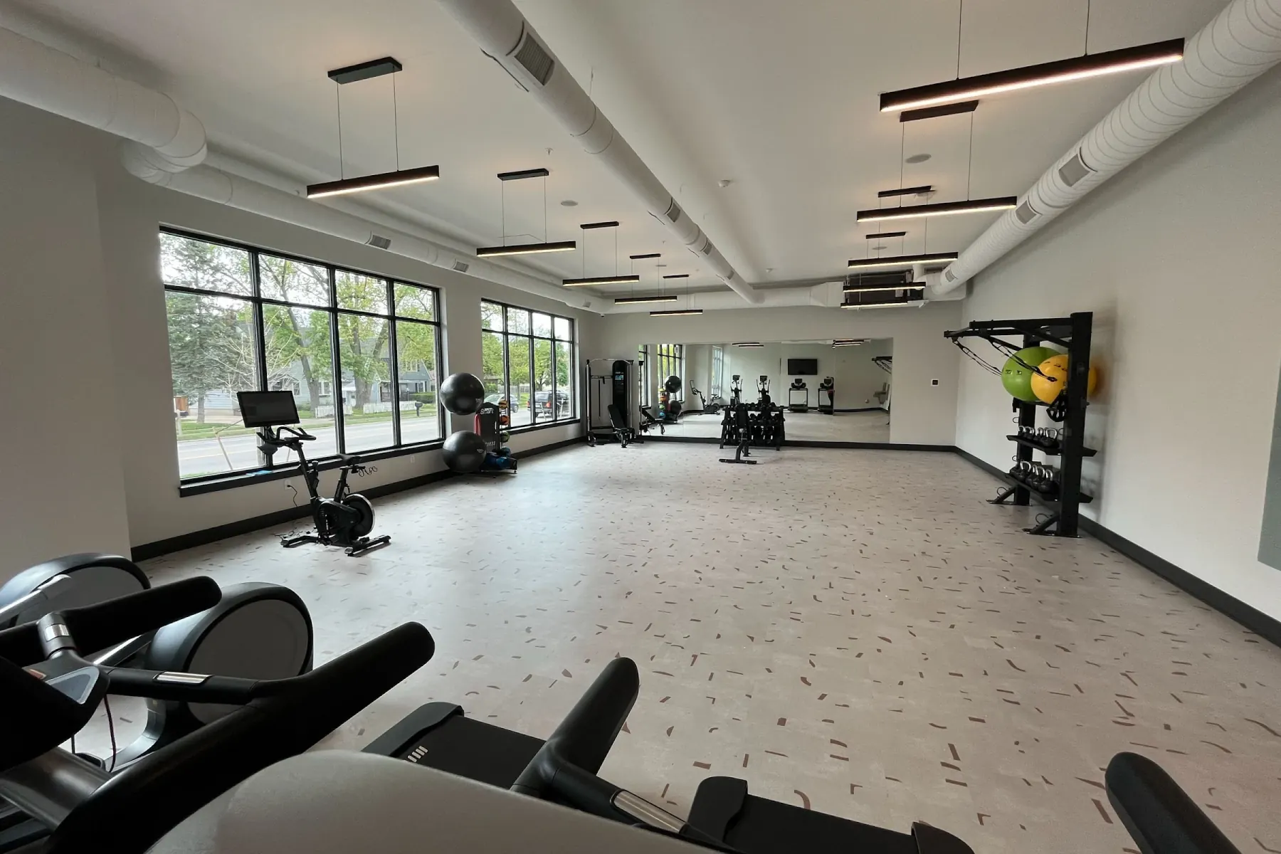 24-hour fitness center at Packard Row with treadmills, ellipticals, dumbbells, stability balls, and a mirrored stretch wall