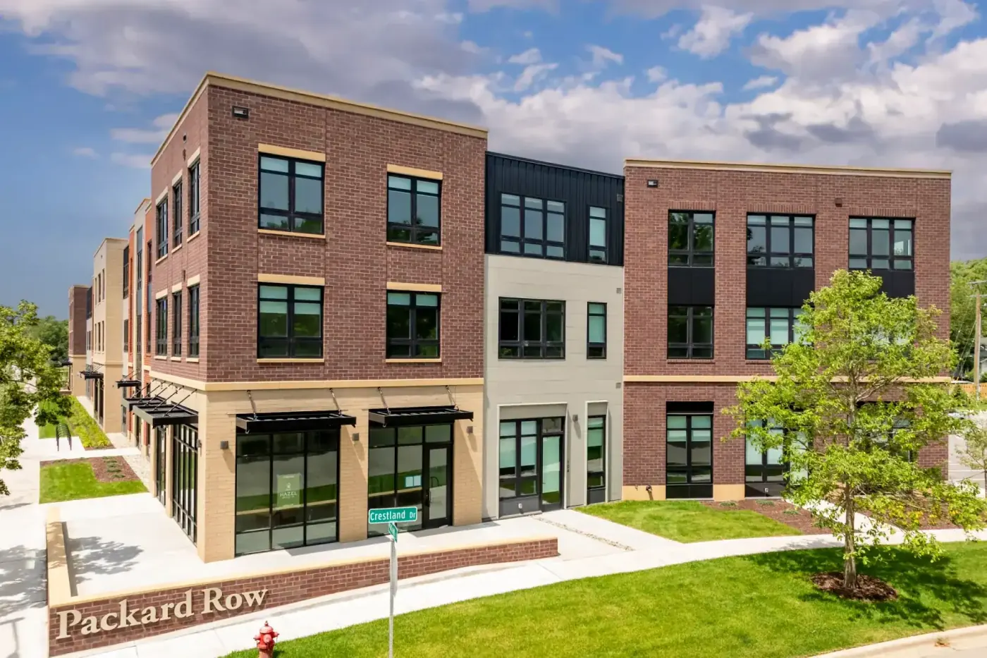 Packard Row Apartments at 2111 Packard Street in Ann Arbor, Michigan — three-story brick building with dark window accents on a sunny day